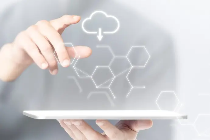 Person using a tablet with cloud icons and hexagonal patterns in the background, symbolizing cloud computing.